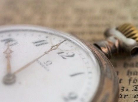 Old pocket watch lying on newspaper, representing time for appointments