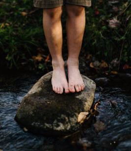 Young and healthy feet standing on rock in gurgling creek, result we want with nursing footcare
